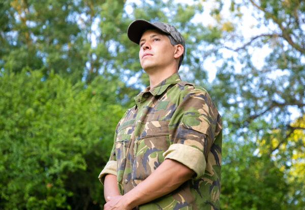 homem-serio-em-uniforme-de-camuflagem-militar-em-pe-no-parque-olhando-para-longe